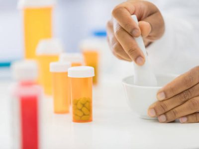 An unrecognizable female pharmacist uses a mortal and pestle to mix a custom medication for a patient.