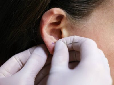 Young woman puncturing her ear. Unrecognizable Caucasian female.
