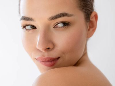 Young and pretty female biting her lips while looking away against white background