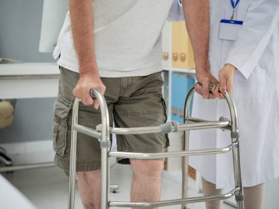 Man making first steps with help of walker after rehabilitation therapy